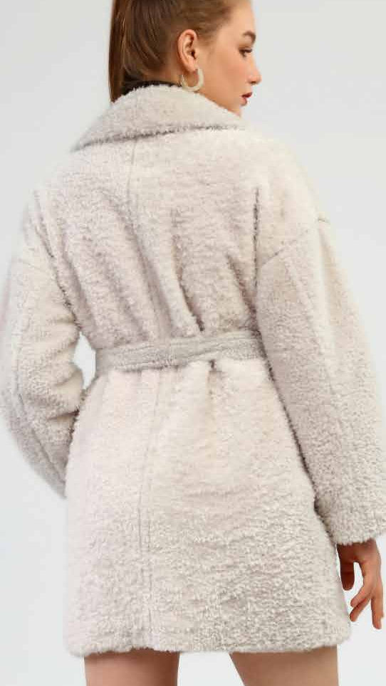 Woman wearing a beige coat and black knee-high boots on a white background