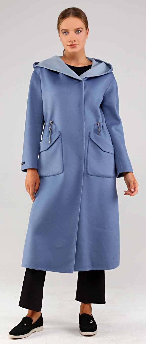 Woman wearing a long blue alpaca coat with a hood on a white background