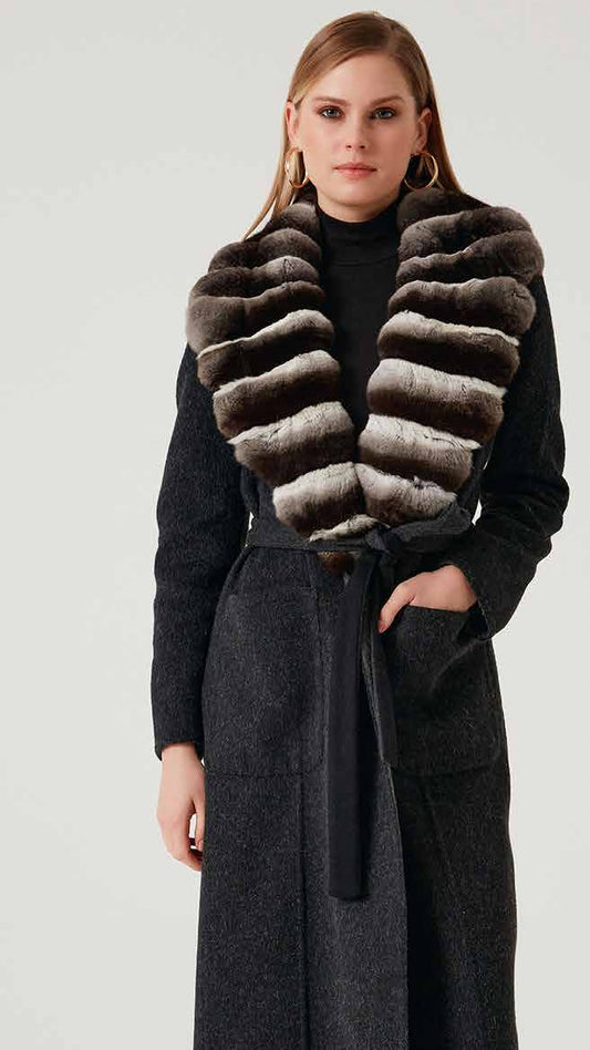 Woman wearing a long dark coat with a fur vest on a white background