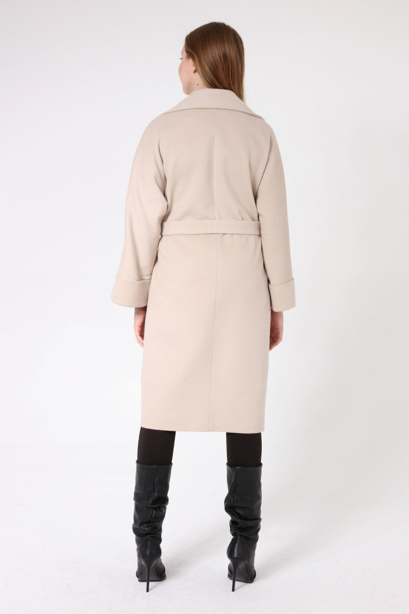 Woman wearing a beige coat and black boots on a white background