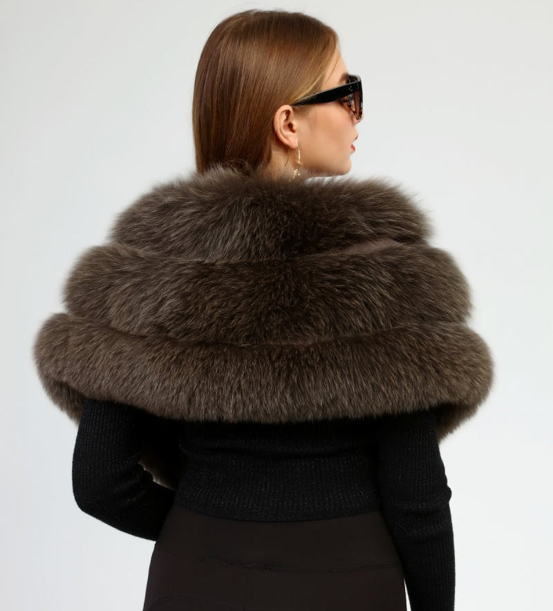Person wearing a black coat with a large brown fox fur shawl on a white background