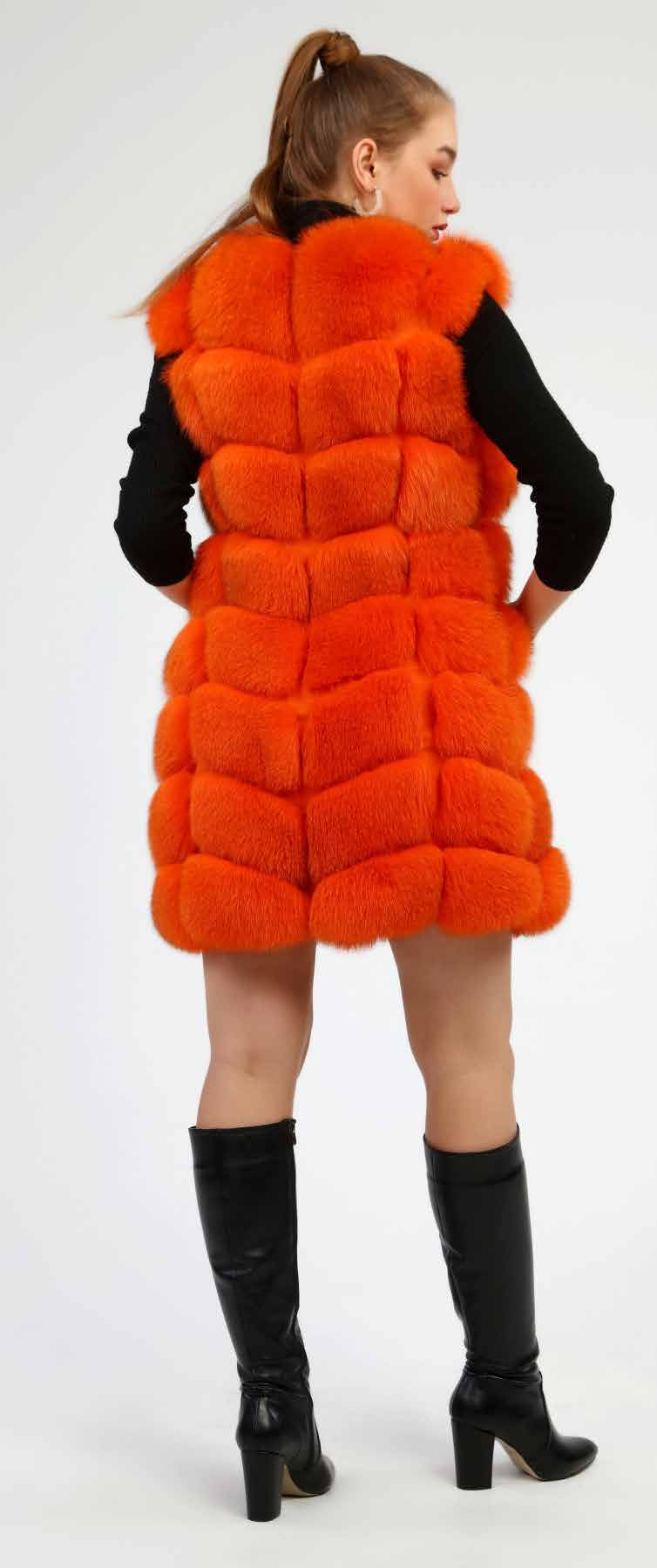 Woman wearing an orange fox fur vest and black boots on a white background