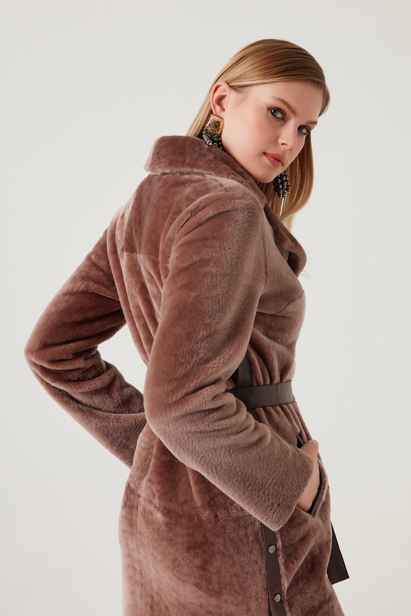 Woman wearing a brown coat against a white background