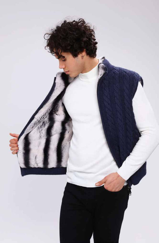 Man wearing a navy blue knitted vest over a white sweater on a light gray background