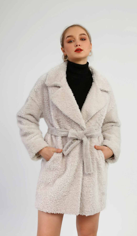 Woman wearing a fluffy beige coat on a white background