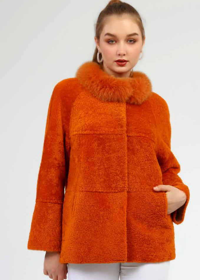 Woman wearing an orange coat, white pants, and white boots on a white background