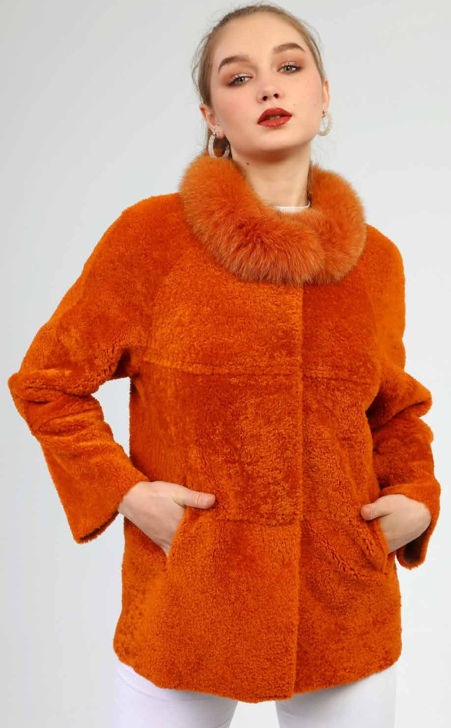 Woman wearing an orange coat with a fur collar on a white background