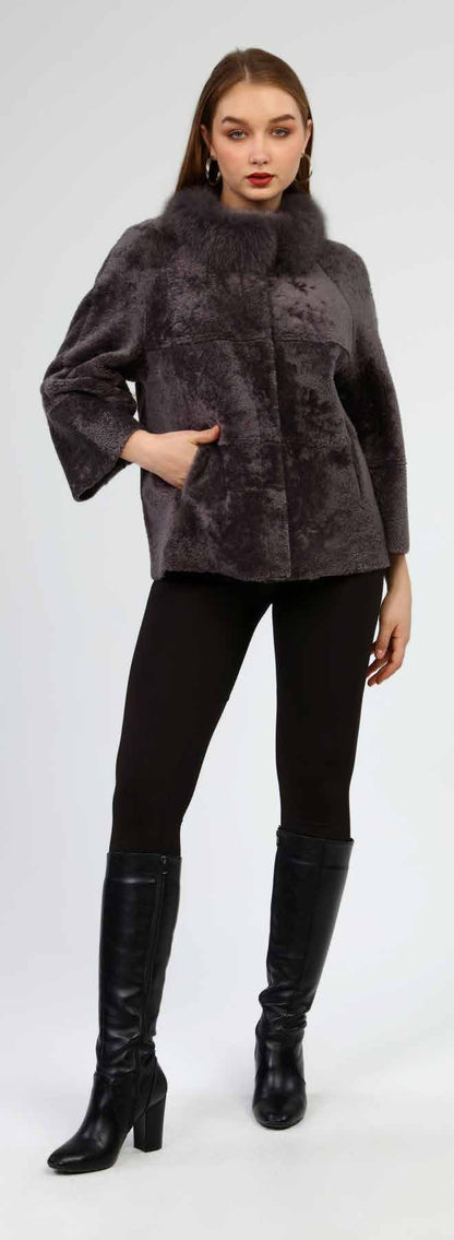 Woman wearing a dark gray fur coat, black leggings, and black knee-high boots on a white background