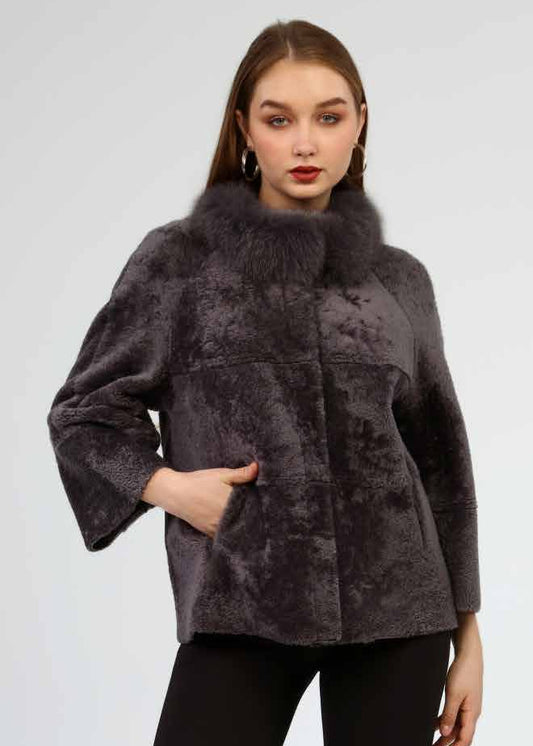 Woman wearing a dark gray fur coat, black leggings, and black knee-high boots on a white background