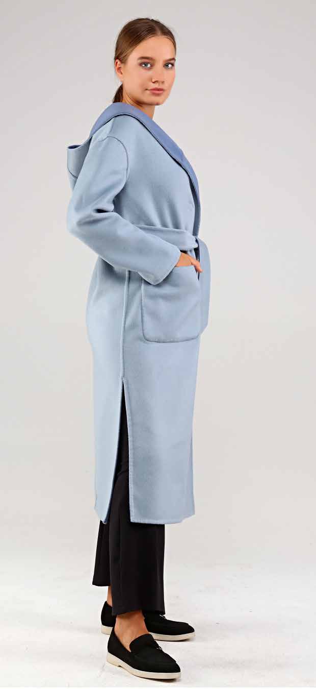 Woman wearing a light blue alpaca coat on a plain background