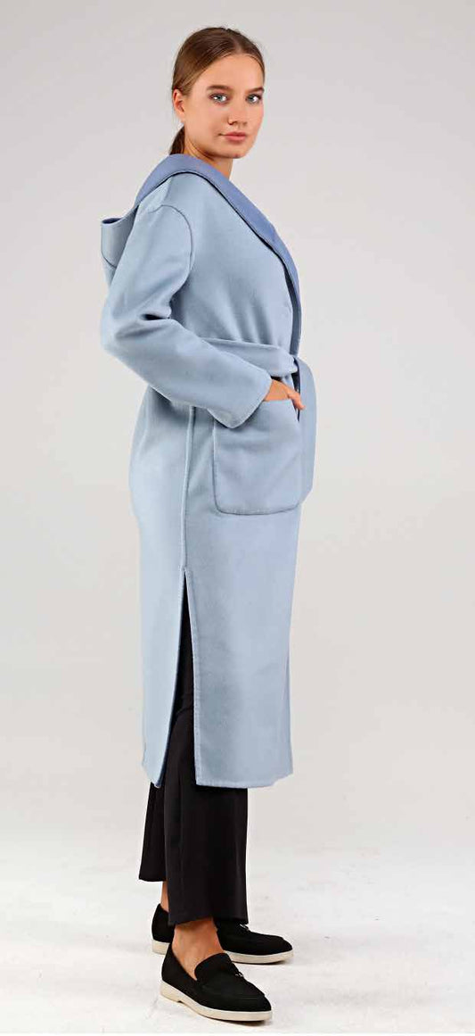 Woman wearing a light blue alpaca coat on a plain background