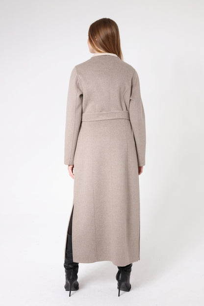 Woman wearing a long beige coat on a white background