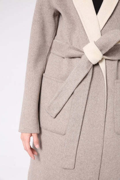 Close-up of a beige coat with a belt on a white background