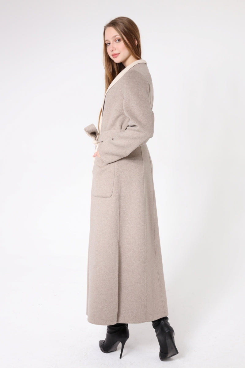 Woman wearing a long beige coat on a white background
