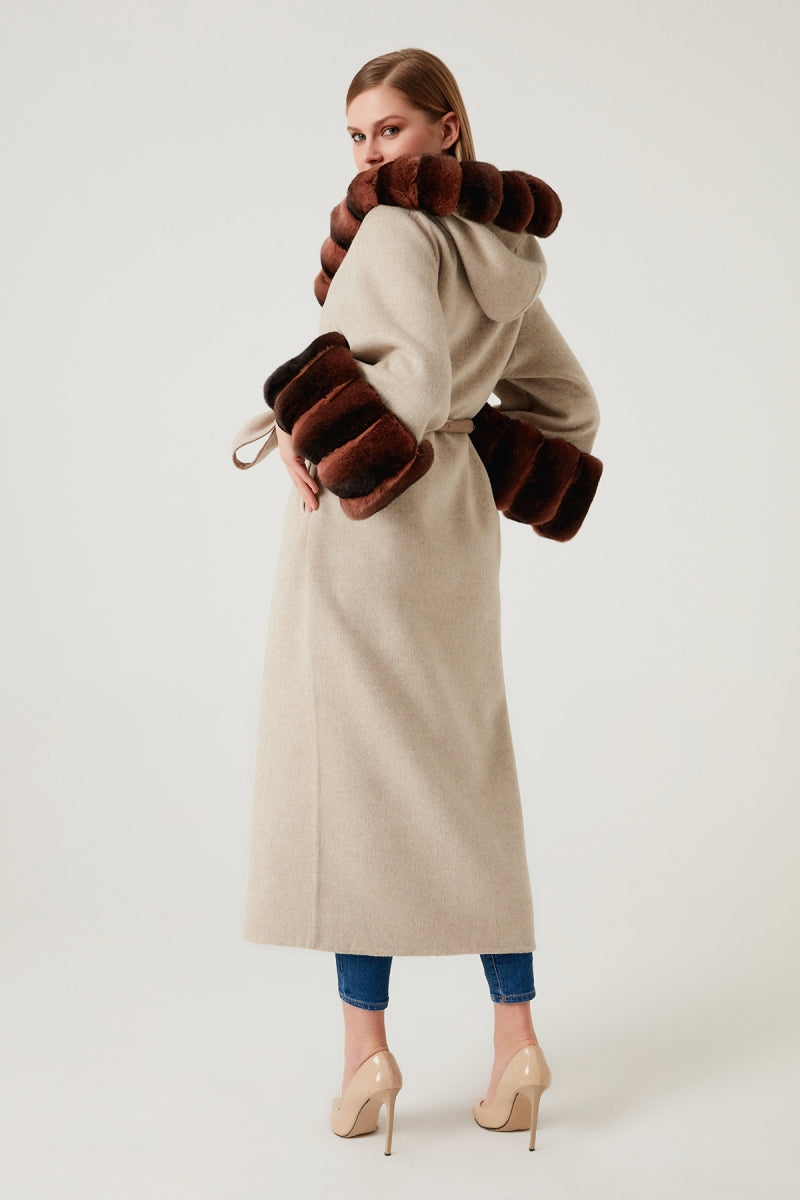 Woman wearing a long beige coat with fur trim on a white background
