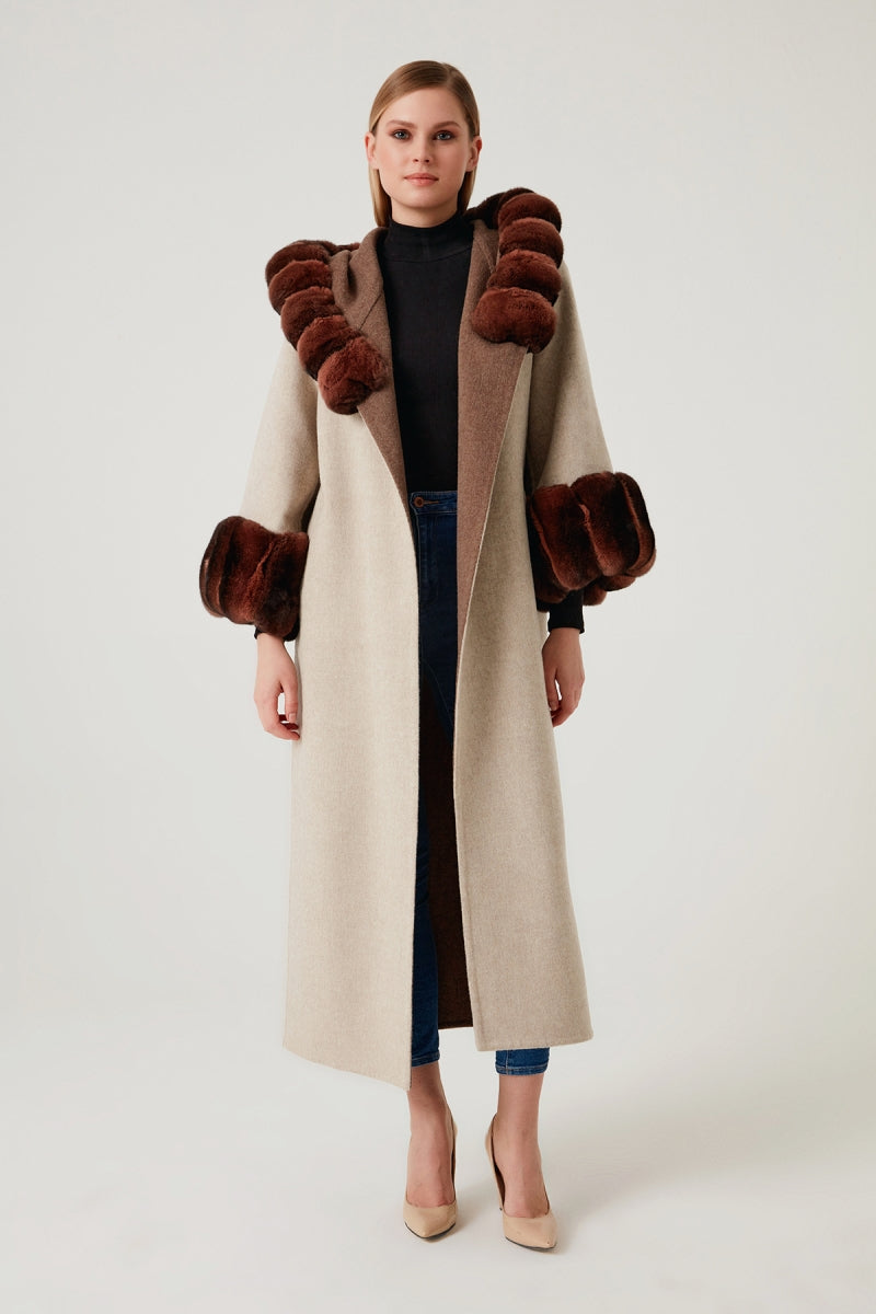 Woman wearing a long coat with fur trim on a white background