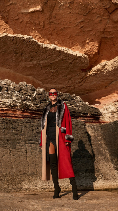 Woman in a red coat standing in a rocky, desert-like landscape