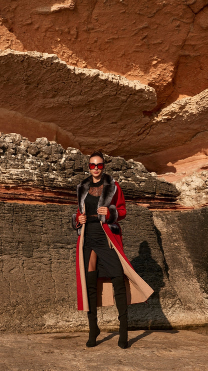 Woman wearing a long coat and sunglasses standing in a desert canyon.