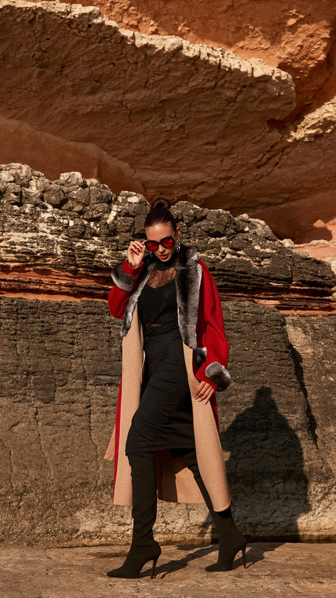 Woman in a red coat with fur trim standing in front of rock formations
