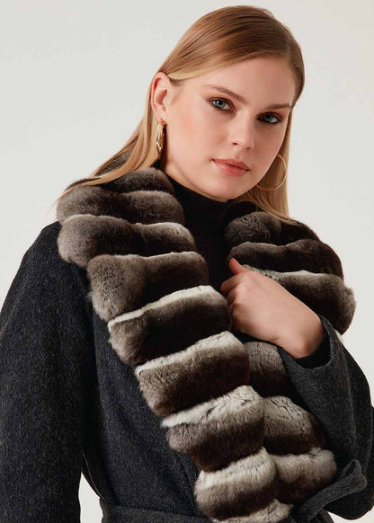 Woman wearing a long fur scarf with a plain background