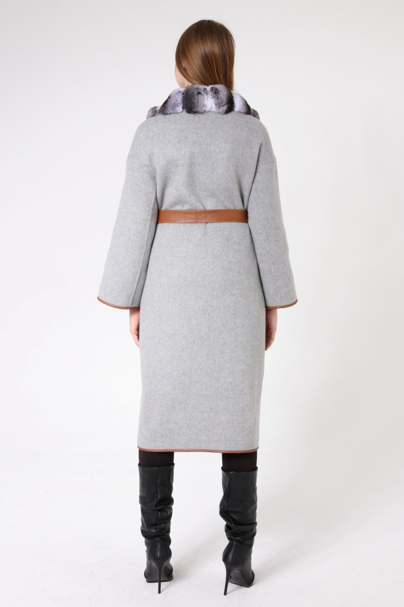 Woman wearing a gray coat with a brown belt on a white background