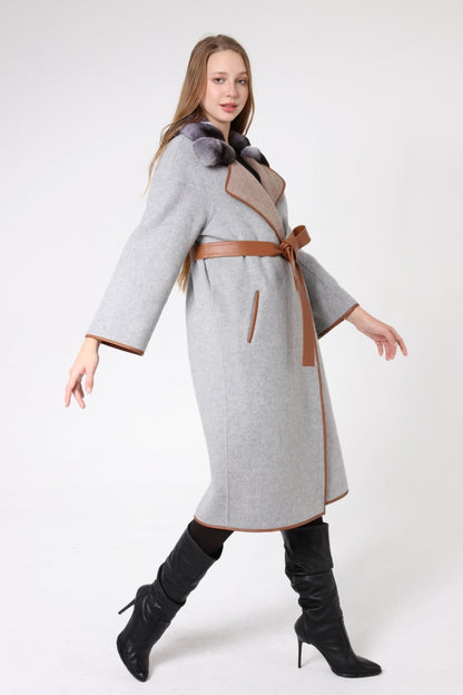 Woman wearing a gray coat with a brown belt and black boots on a white background