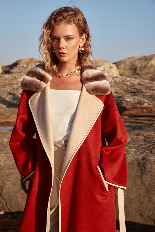 Woman wearing a red coat with fur trim in a rocky outdoor setting