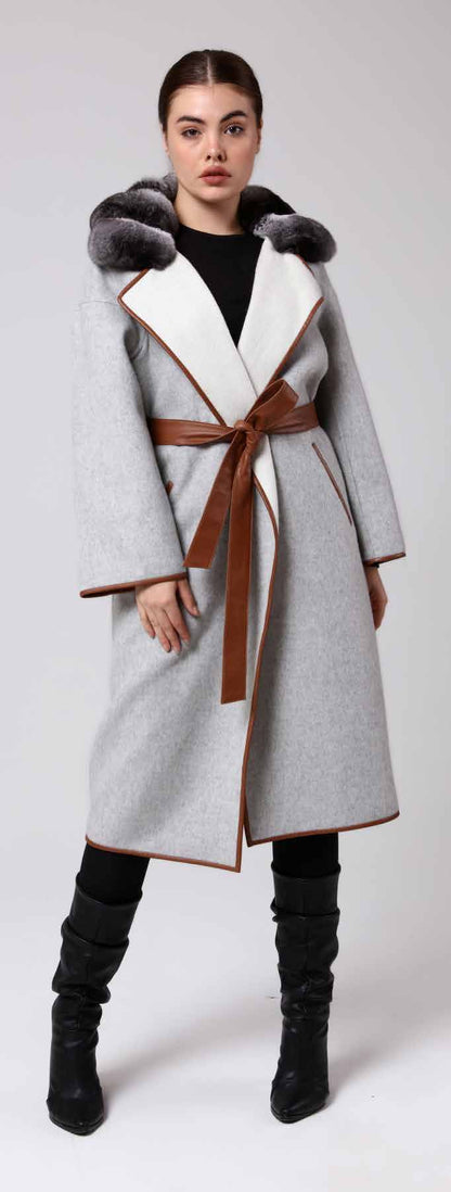 Woman wearing a gray coat with fur hood and brown belt on a white background