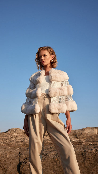 Woman wearing a textured white jacket against a clear blue sky