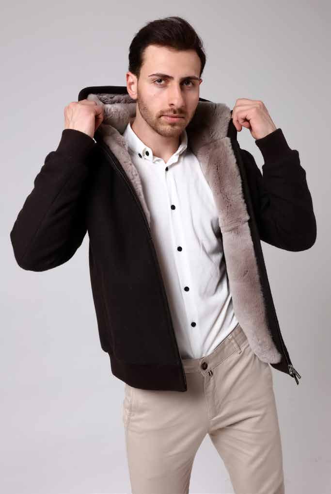 Man wearing a black coat with fur lining on a plain background