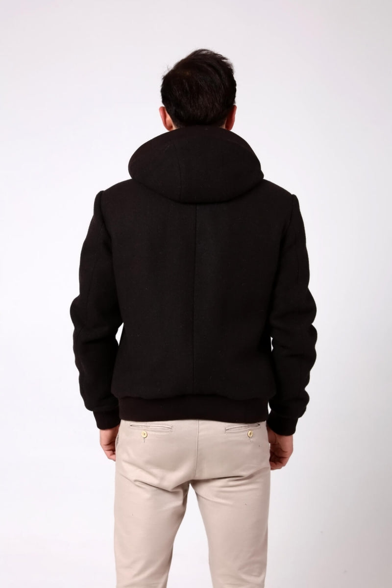 Person wearing a black hoodie and light-colored pants on a white background