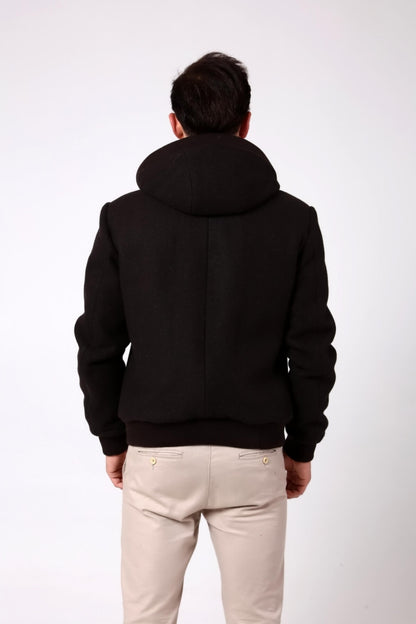 Person wearing a black hoodie and light-colored pants on a white background