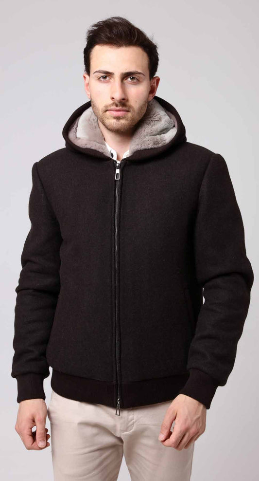 Man wearing a black jacket with a gray hood against a light gray background