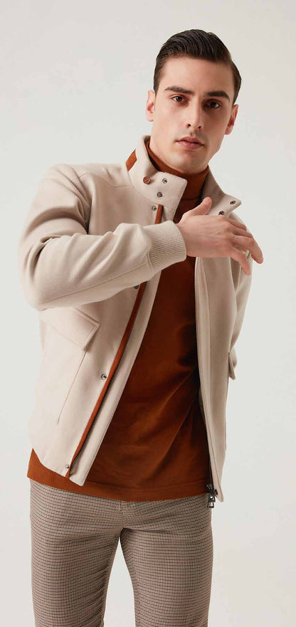 Man wearing a beige jacket over a brown shirt with a white background