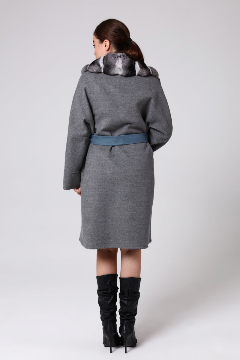 Woman wearing a gray coat with a belt on a white background