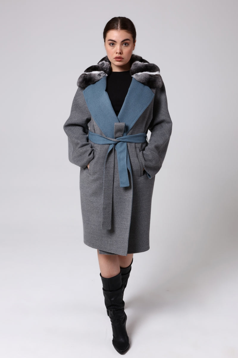 Woman wearing a gray coat with a blue inner lining on a white background