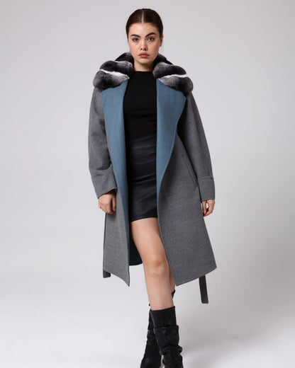 Woman wearing a long gray coat with blue lining on a white background