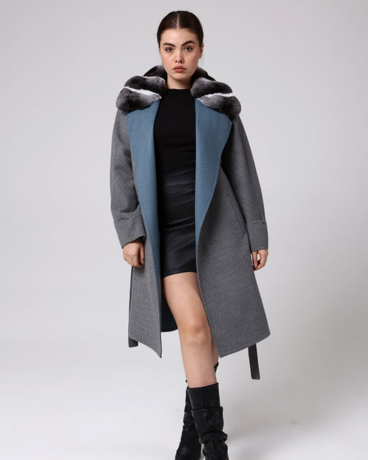 Woman wearing a long gray coat with blue lining on a white background