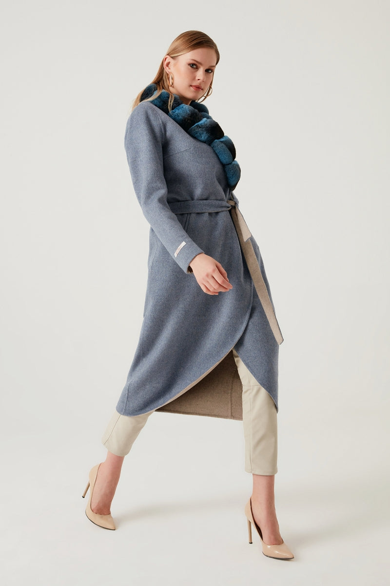 Woman wearing a long blue coat with a white background