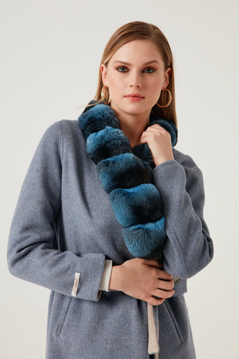 Woman holding a blue fur stole against a white background