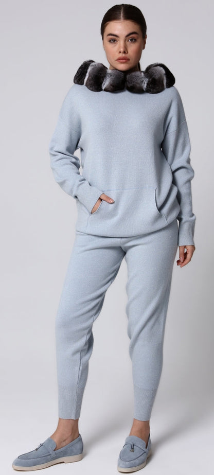 Woman wearing a light blue outfit with a chinchilla fur-lined hood against a white background