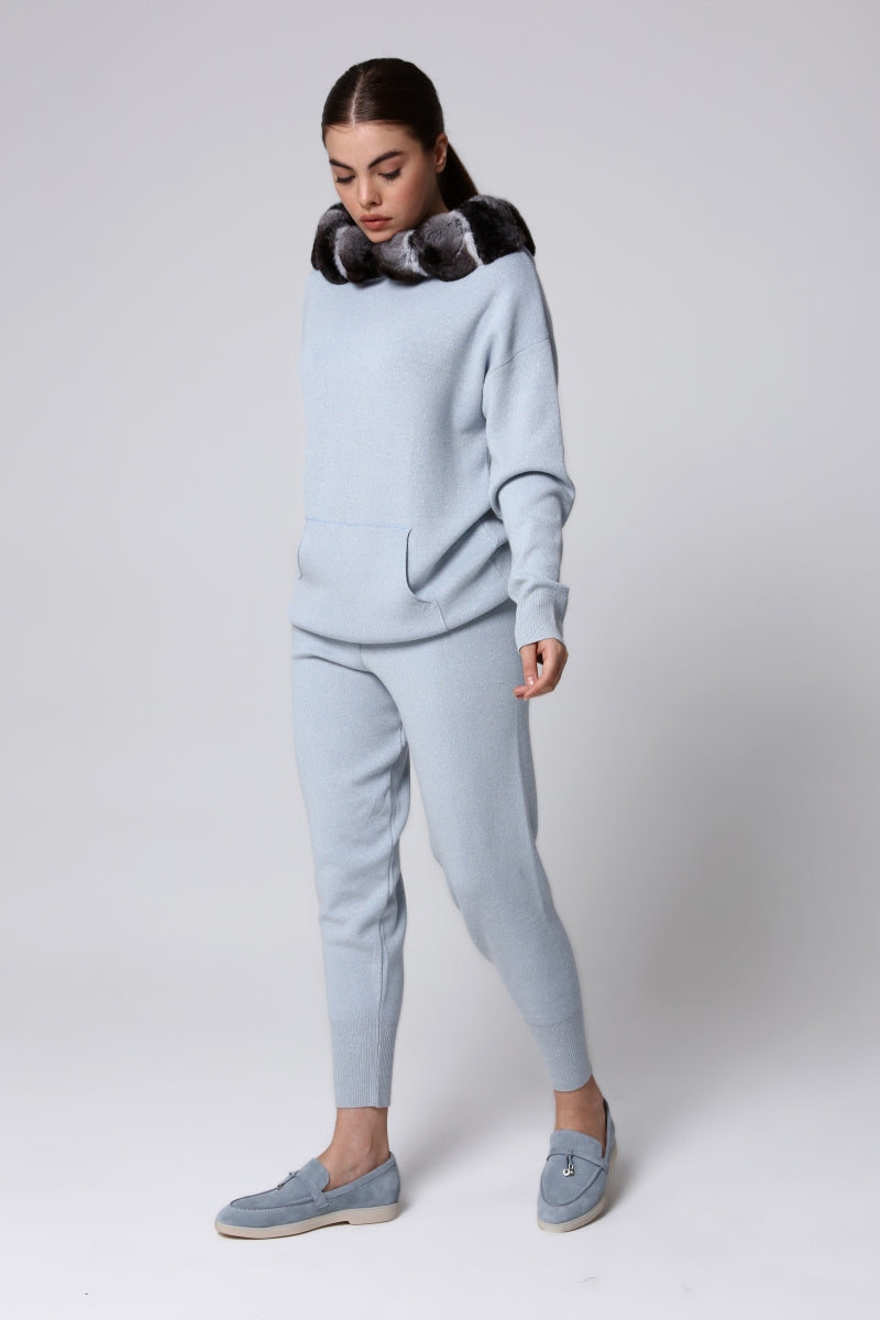 Woman wearing a light blue tracksuit with a chinchilla fur collar on a white background