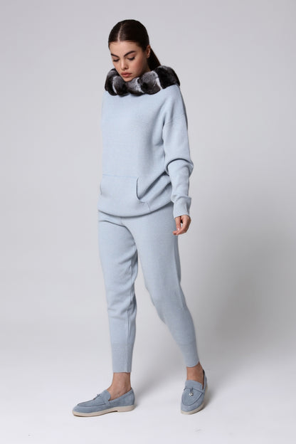 Woman wearing a light blue tracksuit with a chinchilla fur collar on a white background