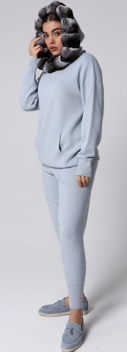 Woman wearing a light blue knitwear with chinchilla fur accents on a white background