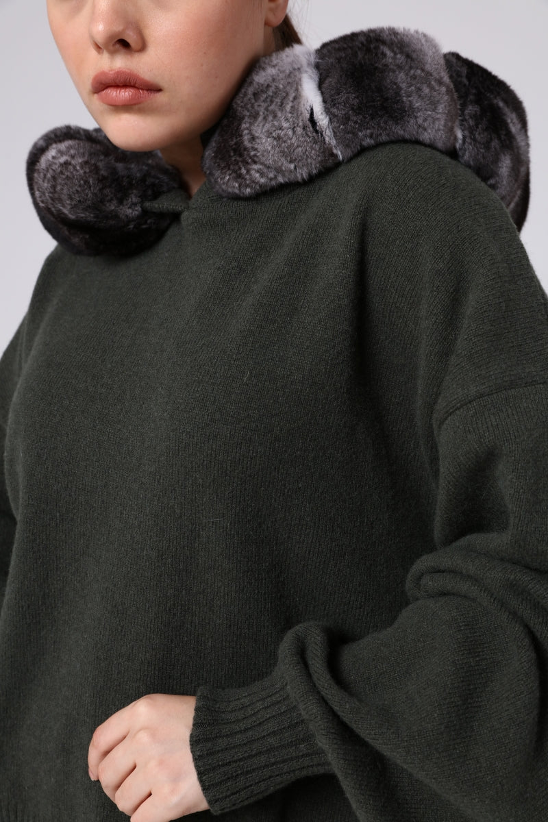 Dark green sweater with chinchilla fur-lined hood and cuffs on a neutral background