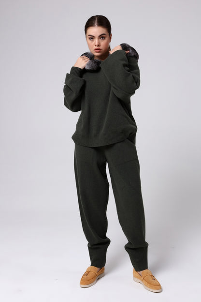 Woman wearing a dark green outfit with brown shoes on a white background