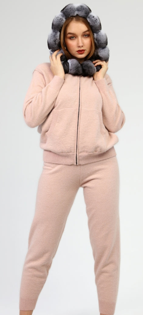 Woman wearing a pink tracksuit with a chinchilla hood against a white background