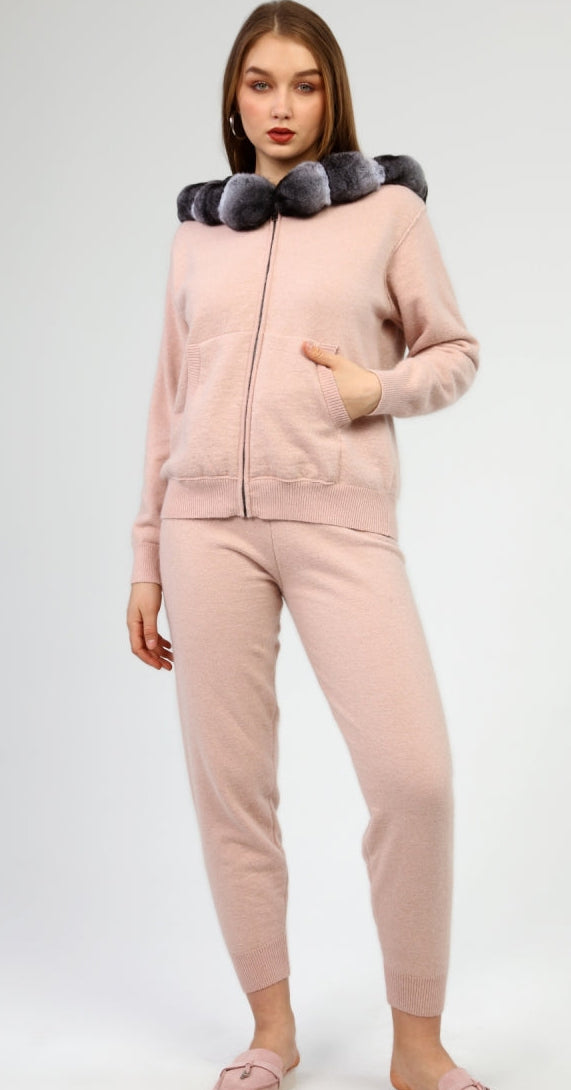 Woman wearing a pink tracksuit with a chinchilla fur-lined hood on a white background