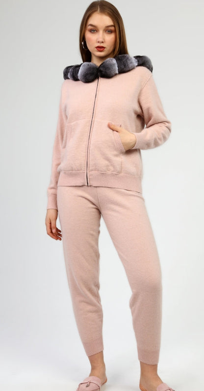 Woman wearing a pink tracksuit with a chinchilla fur-lined hood on a white background