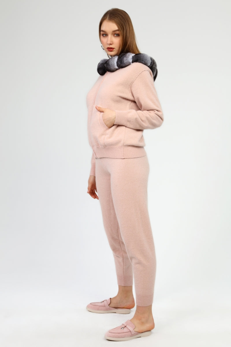 Woman wearing a pink outfit with a chinchilla fur hoodie on a white background